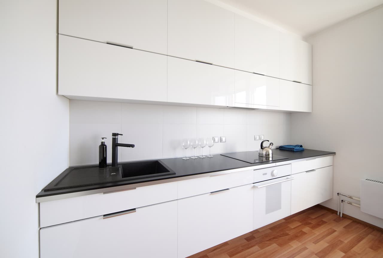 Deep-toned countertops and matte cabinetry with brushed metal hardware.